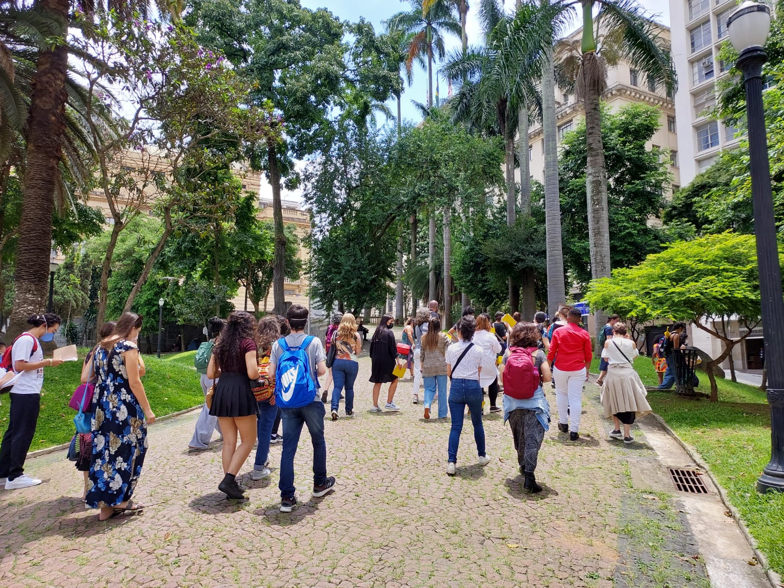 Grupo de pessoas participam de atividade cultural em área externa com árvores e gramado