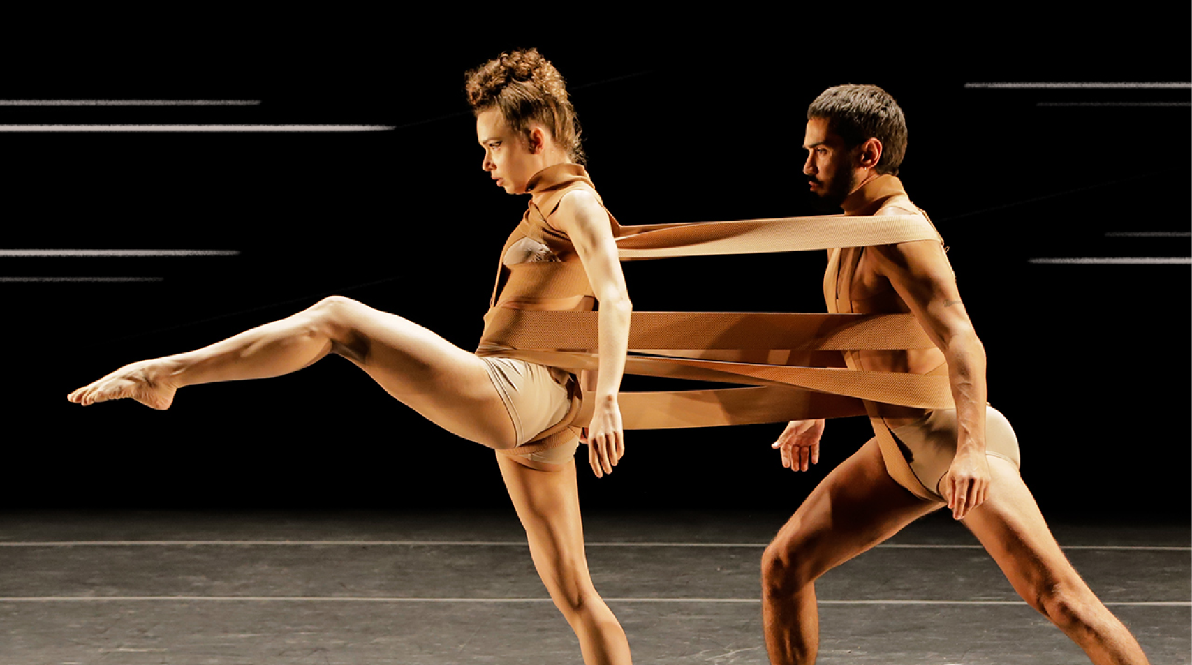 Foto de dois bailarinos em movimento durante coreografia