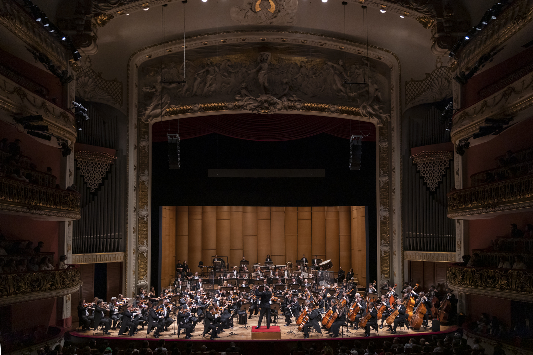 Foto de orquestra completa tocando com maestro a frente