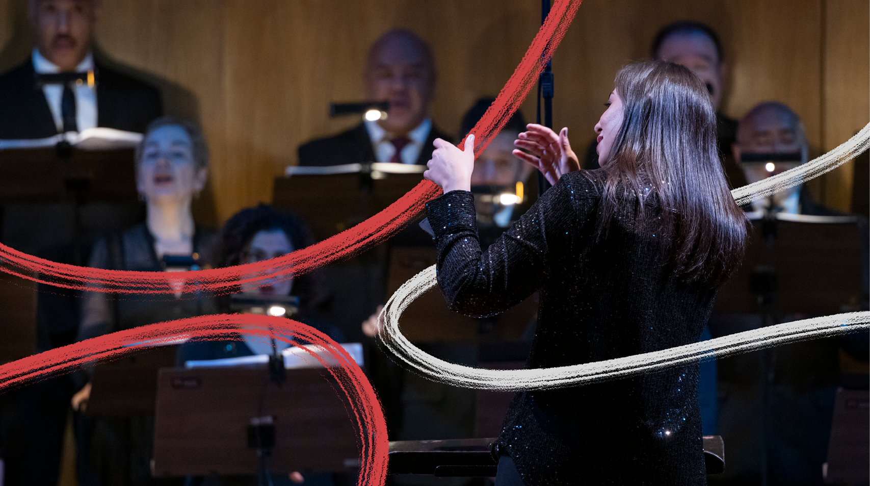 Foto de maestra vestida de preto e com as mãos erguidas regendo um concerto