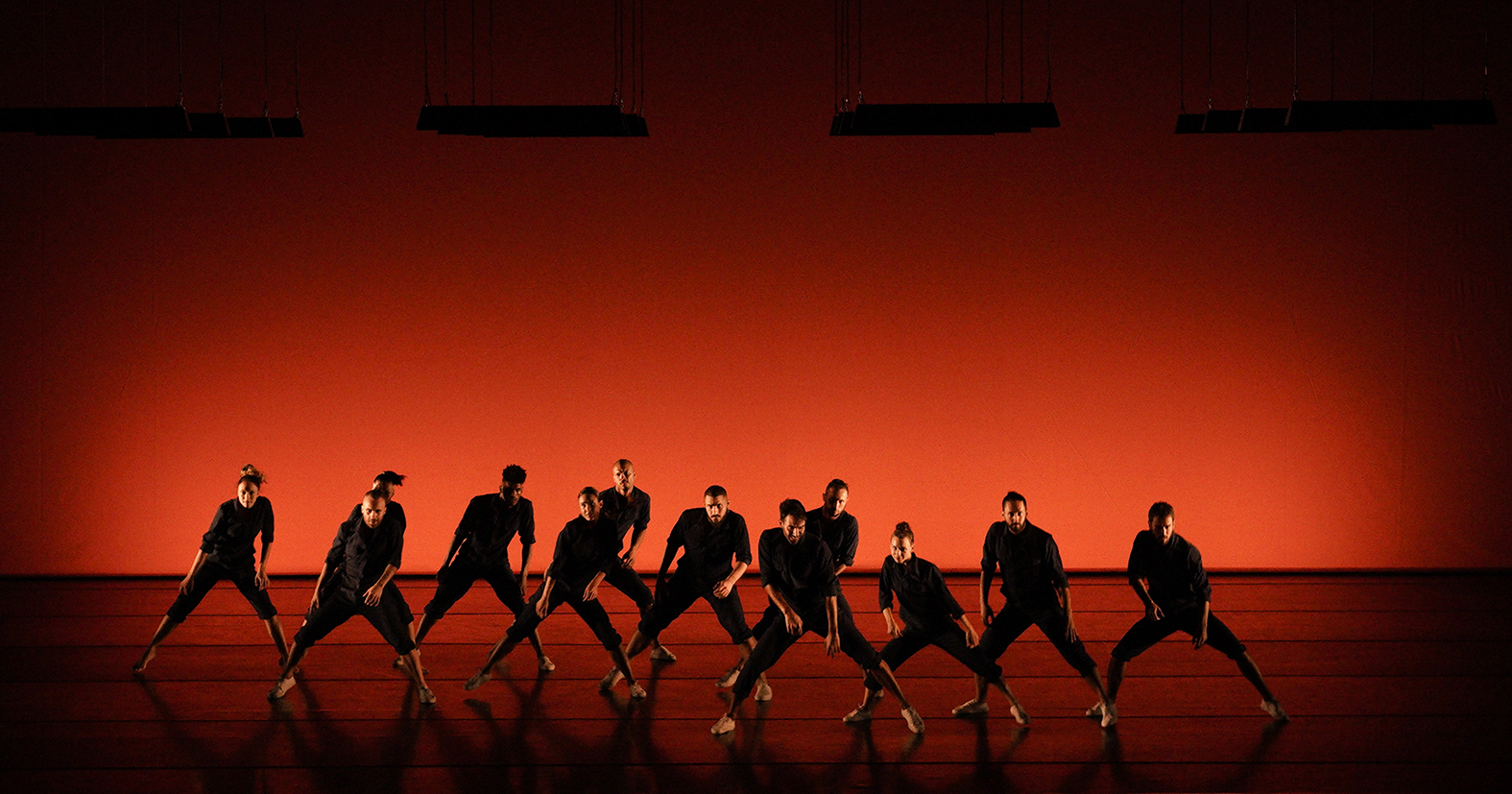 Balé da Cidade dança com roupas escuras num fundo laranja