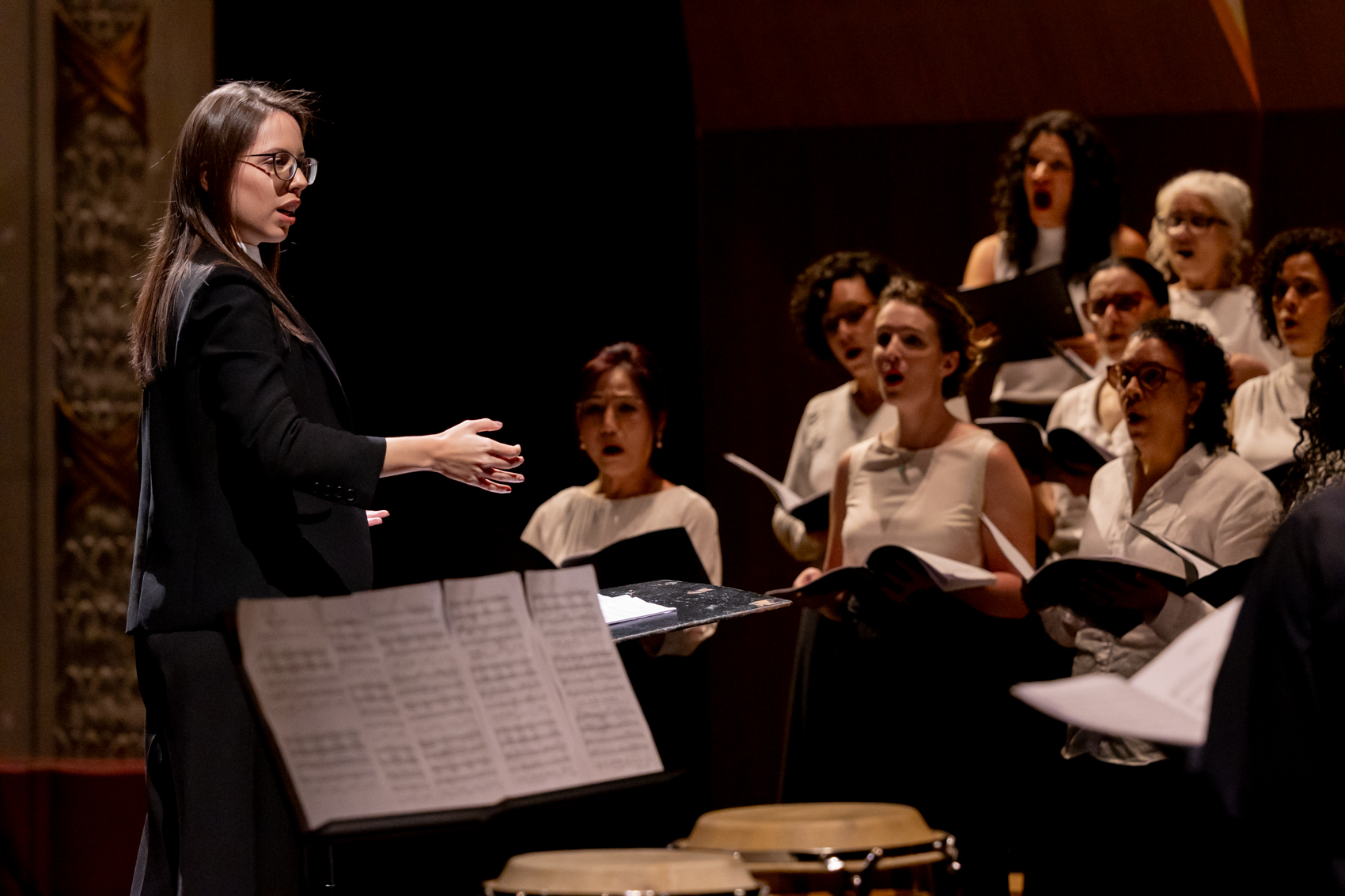 Foto da regente Isabela Siscari regendo o Coral Paulistano durante um concerto