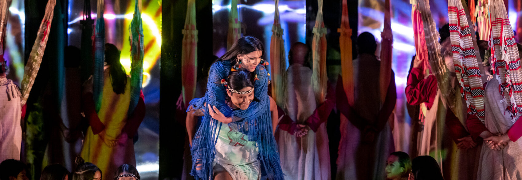 Um trecho da Ópera com duas pessoas indígenas no centro da imagem