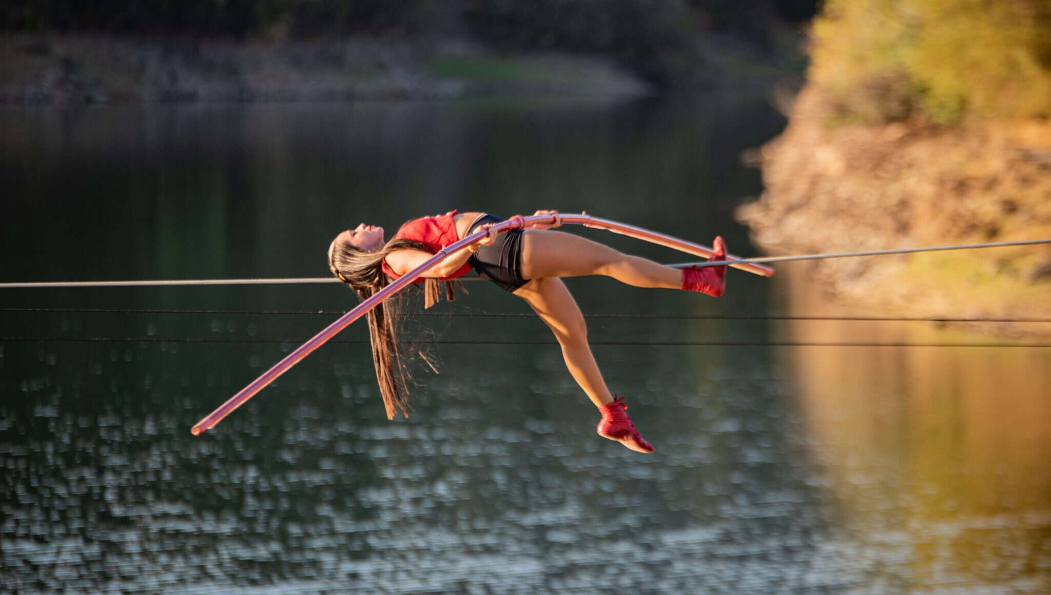 Foto com artista circense atravessando numa corda sob um lago