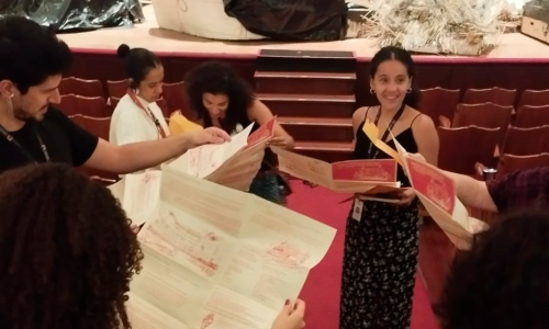 Pessoas em círculo lendo um panfleto sobre o núcleo de educação.